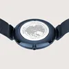 The back of a blue watch with a mesh strap is shown, featuring a world map engraving on the case back. Produktbild-Vorschau