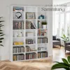 A white bookshelf filled with DVDs, CDs, and decorative items, placed in a room with wooden flooring and large windows. Text overlay indicates 'RAUM FÜR DEINE Sammlung'. Náhled obrázku produktu