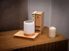 A lamp, two books, and a candle are arranged on a wooden surface. Voir les images du produit