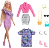 A Barbie doll with multiple outfits and accessories laid out around her. Podgląd zdjęcia produktu