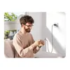 A man is sitting on a couch, playing a game on his phone, which is plugged into a wall charger. Voir les images du produit