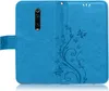 A blue flip case for a smartphone, open to reveal the inside with a floral and butterfly embossed design. Produktbild-Vorschau