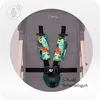 A close-up of a stroller's 5-point harness with decorative padding featuring parrots and butterflies. Produktbild-Vorschau