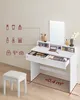 A white makeup vanity with drawers, a mirror, and a stool on a wooden floor, with illustrative icons on the wall. Náhled obrázku produktu
