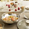 A festive table setting with a frying pan of food, Christmas ornaments, and a lit candle. Voir les images du produit