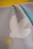 A close-up view of a soft blanket with a dove and olive branch design. Produktbild-Vorschau