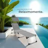 A lounge chair is set up on a patio next to an infinity pool overlooking the ocean. Náhled obrázku produktu