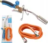 A product shot of a soldering torch and hose, with packaging in the background. Produktbild-Vorschau