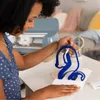 A woman is using a Cricut cutting machine to create a blue vinyl decal. Produktbild-Vorschau