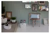 A living room corner with storage baskets, a chair, and decorative items on the wall. Náhľad obrázku produktu