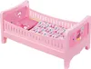 A pink doll bed with bedding. Produktbild-Vorschau