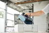A person is holding a cordless orbital sander over its storage case. Voir les images du produit