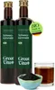 Two bottles of black cumin seed oil, a small bowl of black cumin seeds, and a glass of the oil. Produktbild-Vorschau