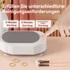 A hand pressing a button on a white ultrasonic cleaner. The cleaner is shown with jewelry and makeup brushes nearby. Text overlays indicate cleaning time options. Produktbild-Vorschau