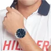 A man wearing a white polo shirt with red lettering and a silver watch with a blue face. Anteprima dell’immagine prodotto