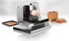 A metal slicer is shown with slices of meat and bread around it. Anteprima dell’immagine prodotto