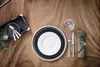 A beautifully set table with plates, cutlery, and a glass on a wooden table. Podgląd zdjęcia produktu