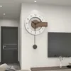 A modern wall clock with a pendulum hangs on a white wall next to a dark gray door and a television. Produktbild-Vorschau