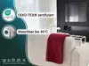 A living room scene with a sofa and a blanket, featuring product certifications and care instructions. Produktbild-Vorschau