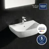 A white sink with a chrome faucet is mounted on a black tiled wall, with a mirror above. There are marketing overlays on the image. Voir les images du produit