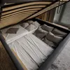 The image shows the inside of a storage bed frame with the mattress lifted, revealing the storage space underneath. The storage space is filled with pillows and bedding. Náhled obrázku produktu