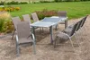 An outdoor patio set with a table and chairs arranged on a gravel surface, with a garden in the background. Produktbild-Vorschau