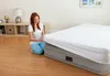 A woman is putting a white sheet on an inflatable mattress. Produktbild-Vorschau