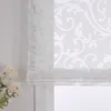 A close-up view of a white sheer Roman blind with a damask pattern, partially drawn, with white flowers in the foreground. Produktbild-Vorschau