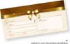 A close-up of a gift certificate with a gold ribbon and bow. Produktbild-Vorschau