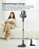 A woman is sitting on a couch reading a magazine while a cordless vacuum cleaner stands upright next to her. A close-up of the vacuum's brush head is shown in a circular inset. Produktbild-Vorschau