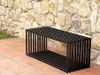 A black metal bench sits on a terracotta tiled patio in front of a stone wall. Anteprima dell’immagine prodotto