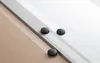 Three black robot vacuum cleaners are shown on a floor with different textures: wood, marble, and a transition strip between them. Produktbild-Vorschau
