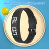 A digital watch with a black band is displayed on a light beige circular platform against a blue background. A yellow sphere is visible in the top left corner. Produktbild-Vorschau