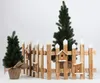 A wooden fence with birdhouses and two small Christmas trees against a white background. Náhled obrázku produktu