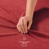 A hand is shown touching a red fabric, likely a bedsheet, with text indicating the material composition. Voir les images du produit