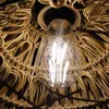 Close-up of a light bulb within a woven lampshade. Produktbild-Vorschau