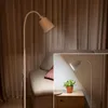 A floor lamp is shown in a living room setting next to a sofa, with an inset image showing the lamp illuminating a small plant on a nightstand. Anteprima dell’immagine prodotto