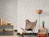 A cozy living room corner with a butterfly chair, a floor lamp, and a shelving unit. Produktbild-Vorschau