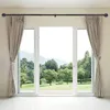 A wide sliding glass door with curtains on either side, revealing a lush green garden and distant mountains. Produktbild-Vorschau