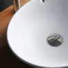 A close-up view of a white ceramic sink with a chrome drain. Produktbild-Vorschau