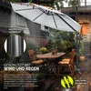 An outdoor patio scene with a large umbrella providing shade over a table and chairs, with rain falling. Produktbild-Vorschau