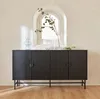 A dark wood sideboard with fluted doors and circular handles, placed against a textured wall with an arched niche. Decorative glass vases and a plant branch are on top. Produktbild-Vorschau