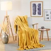A cozy living room scene with a yellow blanket draped over a chair. Voir les images du produit