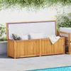 A wooden storage box with cushions and a blanket inside, placed on a patio next to a swimming pool, with greenery in the background. Podgląd zdjęcia produktu