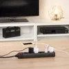 A power strip with multiple plugs and adapters is shown on a wooden table in front of a television stand. Voir les images du produit
