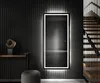 A modern interior with a large, illuminated mirror on a textured wall, next to a staircase. Produktbild-Vorschau