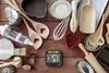 A collection of baking tools and accessories laid out on a wooden surface. Produktbild-Vorschau