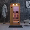 An infrared sauna cabin is shown in a modern bathroom setting, with a bathrobe hanging on a rack and a chair in the background. Produktbild-Vorschau