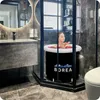 A woman is taking a bath in a portable bathtub filled with rose petals in a modern bathroom. Produktbild-Vorschau