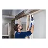 A man is using a Bosch HCS Tauchsägeblatt PAIZ 32 EPC to cut through wood in a construction setting. Produktbild-Vorschau